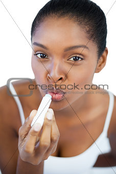 Young woman putting lip balm on her lips