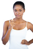 Serious woman with her hand on hip holding lip balm