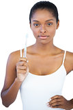 Woman with hand on hip holding her toothbrush