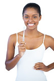 Smiling woman with hand on hip holding her toothbrush