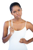 Serious woman with hand on hip holding her toothbrush
