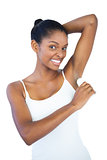 Smiling woman putting deodorant on her armpit
