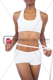 Woman holding apple and measuring her waist