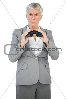 Unhappy businesswoman holding binoculars