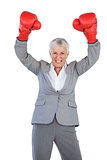 Businesswoman wearing boxing gloves and raising her arms