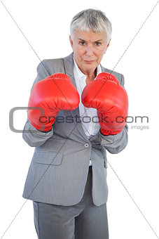 Serious businesswoman standing with her boxing gloves