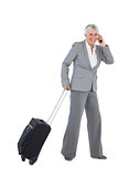 Smiling businesswoman with her luggage and calling someone
