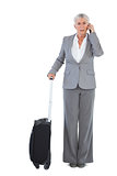 Serious businesswoman with her luggage and calling someone