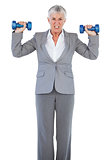 Concentrated businesswoman holding dumbbells