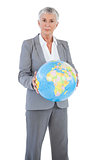 Serious businesswoman holding globe