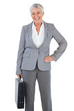 Happy businesswoman holding briefcase and putting her hand on hip