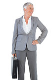 Smiling businesswoman holding briefcase and putting her hand on hip