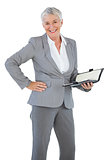 Smiling businesswoman holding diary with her hand on hip