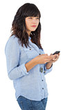 Thoughtful brunette with her mobile phone texting a message