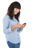 Cheerful brunette with her mobile phone texting a message