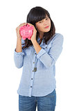 Young woman shaking her piggy bank