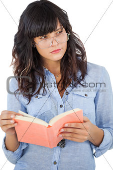 Young woman wearing glasses and thinking about her book