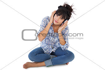 Cute young woman sitting on the floor listening to music