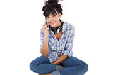 Young woman sitting on the floor with headphones calling someone