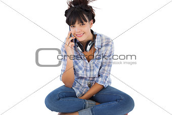Young woman sitting on the floor with headphones calling someone