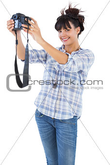 Smiling brunette taking picture with her camera