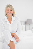 Blonde woman sitting cross legged  in her bedroom