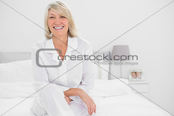 Happy woman sitting cross legged  in her bedroom