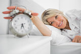 Blonde woman turning off ringing alarm clock