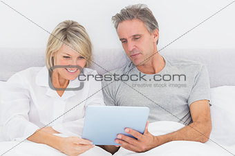 Happy couple using tablet pc in bed