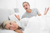 Man pleading with his upset partner in bed