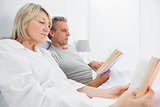 Relaxed couple reading books in bed