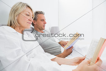 Relaxed couple reading books in bed