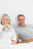 Relaxed couple watching tv in bed