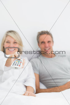 Relaxed couple watching tv in bed