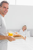 Happy man bringing breakfast in bed to his partner