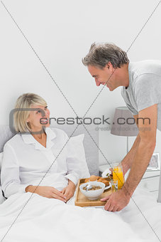 Considerate man bringing breakfast in bed to his partner