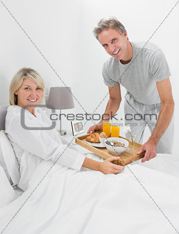 Happy man giving breakfast in bed to his partner