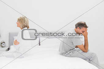 Couple sitting on opposite sides of bed