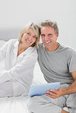 Couple using their tablet pc smiling at camera