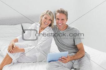 Couple using their digital tablet smiling at camera