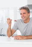 Cheerful man having cereal for breakfast in kitchen
