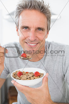 Happy man eating cereal for breakfast