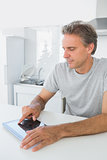 Smiling man using tablet pc in kitchen