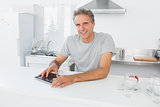 Happy man using tablet pc in kitchen