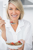Happy woman eating cereal for breakfast