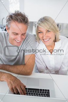 Smiling couple using their laptop in the morning