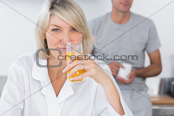 Woman drinking orange juice in kitchen