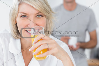 Happy woman drinking orange juice in kitchen
