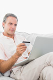 Man on his couch using laptop for shopping online