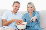Couple watching tv and eating popcorn on the couch